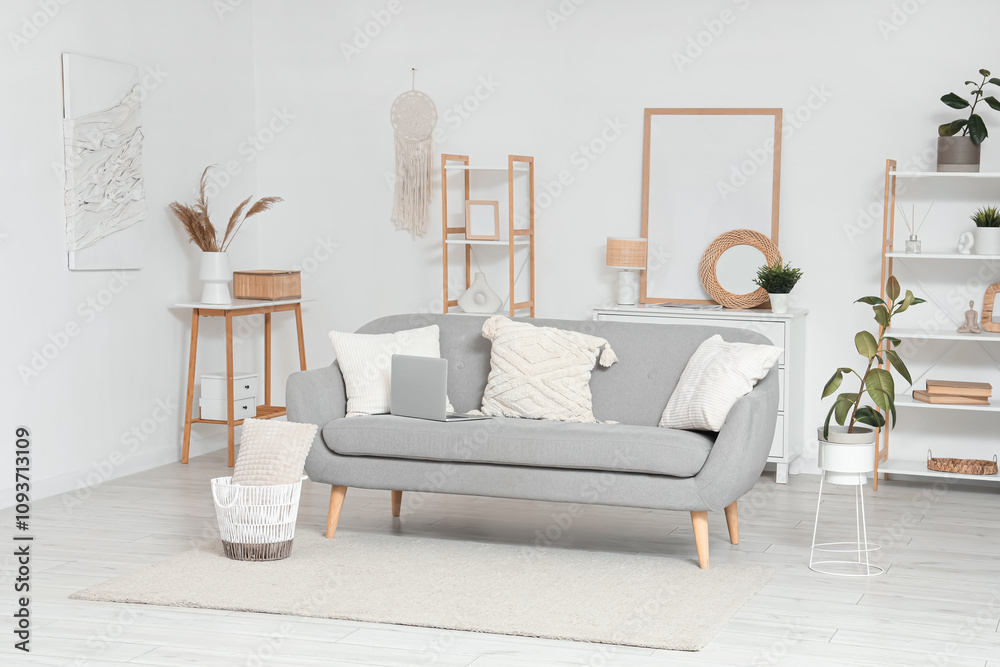 Interior of light living room with grey sofa and shelf units