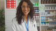 © Krakenimages.com - Smiling woman pharmacist standing in a well-stocked, modern drugstore with shelves of medications