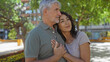© Krakenimages.com - Middle age couple embracing lovingly in a sunny urban park, showcasing their strong relationship and the beauty of togetherness outdoors in a vibrant city setting.