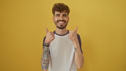 Handsome hispanic man with beard giving thumbs up against yellow background