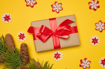 Wall Mural - Gift box with red satin ribbon and bow on a yellow background. Holiday background