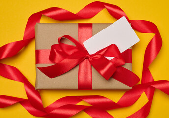 Wall Mural - Box tied with red ribbon on yellow background, festive background