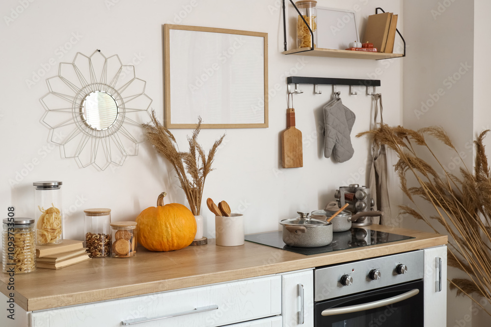 Pumpkin with pampas grass and food on counter in light kitchen interior