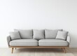 © adri - A gray sofa with wooden legs in front of a white wall.