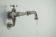 © Tanakrit - A vintage faucet with running water, showcasing a classic design against a simple background.