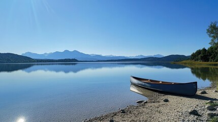  A serene lake scene with a canoe on the shore and mountains in the background.