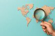 © Rutchaneewan - Exploring Global Investments, a hand examines a world map with a magnifying glass, uncovering hidden financial prospects and opportunities.