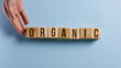 © Katsiaryna - organic word on a blue background written on a wooden block. organic text on the table, concept.