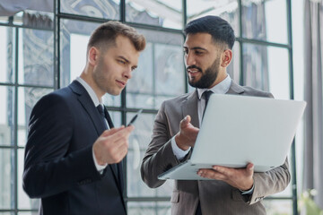 two professional businessmen discussing and using desktop computer in office