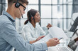 © Katsiaryna - young man using a headset and computer in a modern office
