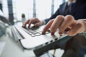 Wall Mural - Closeup image of a man working and typing on laptop computer keyboard