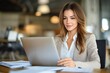 © Yuliya - Professional Business Woman with Laptop in Office Reviewing Documents and Smiling