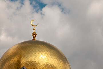 Gilded dome of a mosque with a crescent moon against the sky