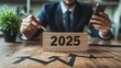 © MSH - Businessman using a smart phone to write the text 2025 business graph chart