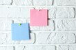 © Sunlight - Colored stickers attached with pushpin on a white brick wall. Collection of sheets of paper of different colors, ready for message