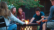© Monkey Business - Group Of Teenage Friends Outdoors At Party Toasting Marshmallows Over Fire Pit
