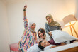 © Odua Images - A lively group of friends having fun during a pillow fight in a stylish bedroom.