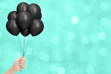 Aufkleber - Female hand holds bunch of black balloons on blurred background. Empty space for text
