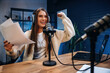 © standret - Front view, sitting. Woman is hosting radio podcast with microphone and laptop