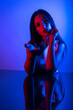 © FATIR29 - High Fashion model woman in colorful bright neon blue and purple lights posing in studio. Portrait of beautiful woman with trendy glowing make-up. Art design vivid style