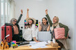 © Odua Images - A group of cheerful friends celebrates their exciting travel plans in a busy office