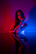 © FATIR29 - High Fashion model woman in colorful bright neon blue and purple lights posing in studio. Portrait of beautiful woman with trendy glowing make-up. Art design vivid style