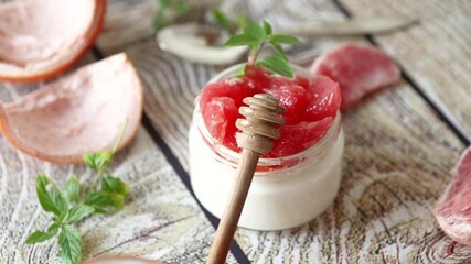 Poster - homemade sweet yogurt in a glass jar with pieces of red ripe grapefruit and honey, on a wooden table