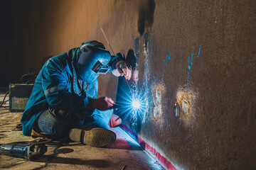 Welders at work in metal argon industry, welding metal plate tank construction close up wear protective gloves and mask in side confined