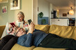 © Marko Geber - Senior couple relaxing on couch and using smartphones together