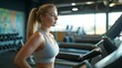 © Valentyna Prudnikova - Focused and determined, a young woman with blonde hair in a ponytail exercises on a treadmill at the gym, surrounded by fitness equipment and weights.