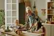 © AnnaStills - Elderly woman helping two young girls prepare breakfast in warm and inviting kitchen setting, with family bonding moment highlighted by natural interaction and cheerful atmosphere