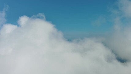 Wall Mural - Flying through beautiful white fluffy clouds in sky over blue sea. Airplane travel background, 4k