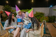 © Odua Images - A group of friends enjoys a festive night outdoors, wearing colorful hats and having fun