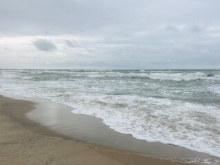 Wall Mural - cloudy seascape, sandy shore, empty wild beach, clouds and waves