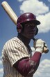 © Georgii - Determined American baseball player in striped uniform holding bat under sunny sky