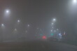 © Marat - A foggy street at night with bright streetlights illuminating the road.