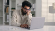 © Yuliia - Tired bored Arabian Indian man businessman lazy employee manager boring job working with laptop studying write business project depression burnout fatigued overworked drowsy sleepy male guy at office