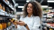 © Pinklife - A smiling woman is happily examining a bottle of olive oil in a store aisle, symbolizing joy, selection, and the pleasure of finding quality products.