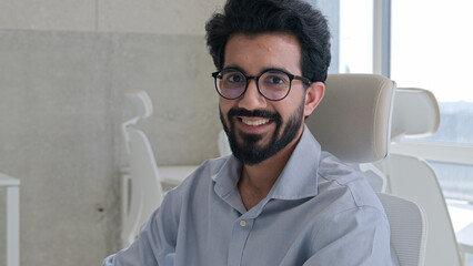 Indian muslim man Arabian businessman entrepreneur office worker manager employer CEO executive programmer business working with laptop computer at modern office workplace looking camera toothy smile