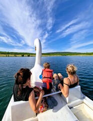 Two women and a boy ride a swan-shaped pedal boat. Milada Lake, Czech Republic, Europe.