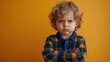 ©  Dreamy Shots - Frustrated boy with curly hair crossing arms, unhappy expression, modern childhood portrait, emotional body language, serious mood, casual gray shirt, lifestyle, emotions, childhood attitude