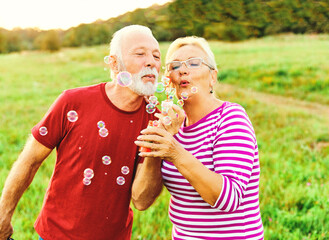 Wall Mural - woman man outdoor senior couple happy fun retirement together bubble soap blowing love old nature ma