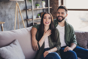 Wall Mural - Photo of positive married people wife husband sitting on couch together modern loft interior living room flat indoors