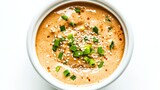A bowl of creamy sesame ginger dressing garnished with sesame seeds and green onions, Each spoonful flavorful and aromatic