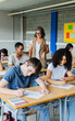 © Xavier Lorenzo - Mature female teacher helping young black high school student in classroom. Diverse group of young teenagers boys and girls doing an academic exam. Education and back to school concept.