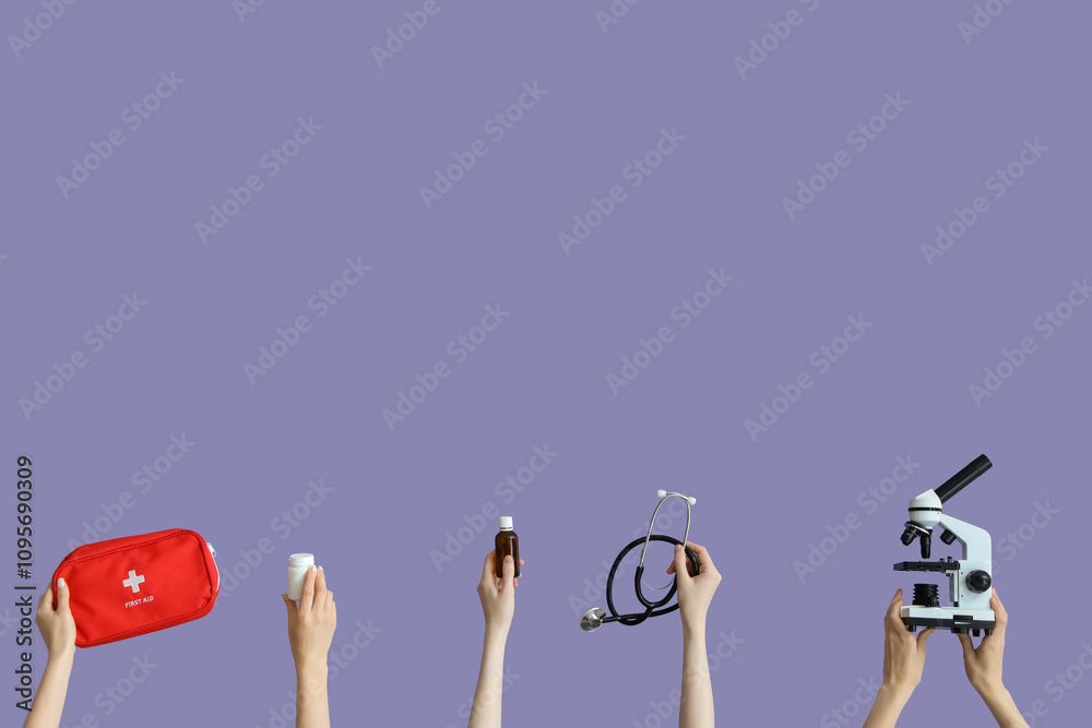 Hands with first aid kit, stethoscope, microscope and pills on lilac background