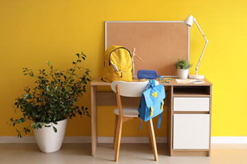 Wall Mural - Workspace with school supplies and backpack near yellow wall