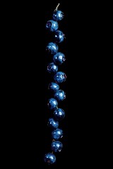 Poster - A vertical arrangement of shiny blue ornaments on a black background.