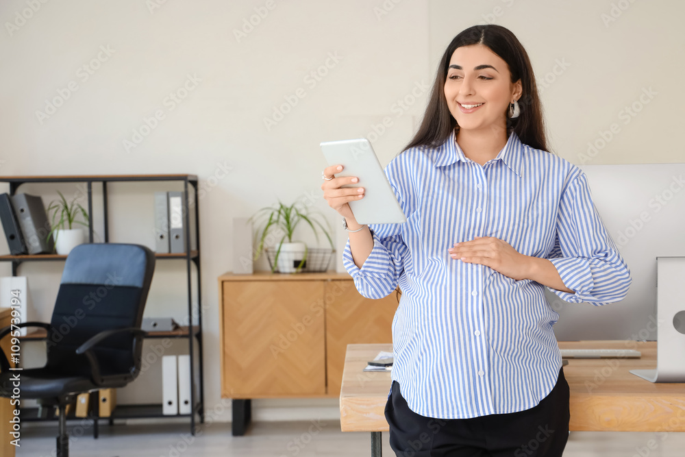 Pregnant businesswoman with tablet computer smiling in office