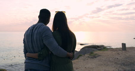 Wall Mural - Sunset, beach and couple in embrace on romantic date, holiday adventure or sightseeing from back. Evening sky, man and woman on travel vacation with love, view or outdoor journey together at ocean